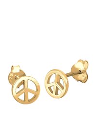 Boucles d'oreilles en métal doré en forme de signe de la paix. Forme circulaire avec des découpes et une texture lisse. Fermoir en métal inclus.