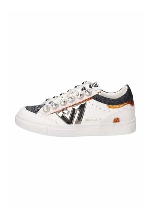 Sneaker bianco con accenti neri e rame, dettagli glitterati, faux gemme sulle stringhe e una suola liscia e testurizzata. Nome del marchio visibile.