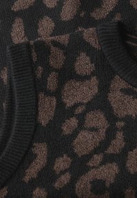 Braunes und schwarzes Strickgewebe mit einem Leopardenmuster. Strukturiert Oberfläche mit gerippten Kanten. Nahaufnahme, die die Details hervorhebt.