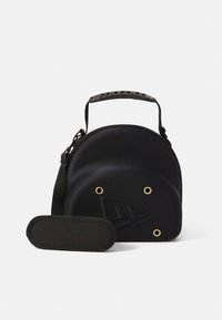 Svart rund väska av texturerat material med guldfärgade öljetter, svart rem och en avtagbar oval väska. Har en minimalistisk design.