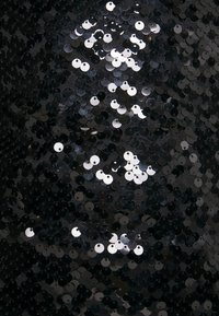 Tissu noir à paillettes présentant des paillettes rondes et brillantes avec des surfaces réfléchissantes, densément agencées, créant un aspect texturé et scintillant.