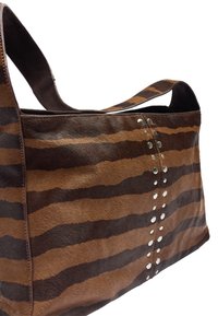 Brązowo-beżowa torebka w paski wykonana z miękkiego futra zwierzęcego, ozdobiona srebrnymi ćwiekami wzdłuż szwu oraz solidnym paskiem na ramię.