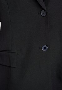 Black blazer featuring a smooth fabric texture, a single row of button closures, and a chest pocket with a straight flap.