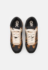 Las zapatillas presentan una parte superior de ante con estampado de leopardo, detalles en cuero negro y cordones beige. La suela exterior tiene textura para un mejor agarre.