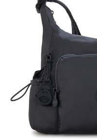 Black nylon shoulder bag with a smooth texture, featuring a zippered pocket and a monkey-shaped zipper pull for added detail.