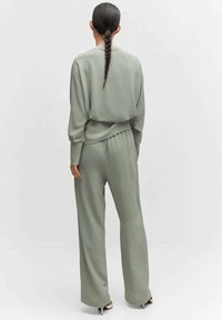 Ensemble de loungewear vert, texturé, comprenant un haut à coupe décontractée avec des manches tombantes et un pantalon large taille haute.