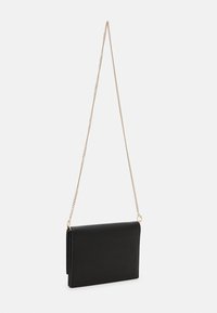 Svart clutch-veske med teksturert overflate, gullkjede-reim og rektangulær form. Har en fold-over design med minimalistisk stil.