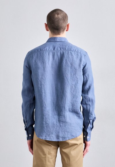 Camisa de lino azul con un corte relajado, mangas largas, cuello puntiagudo y puños con botón. Tejido texturizado con un aspecto ligeramente arrugado.