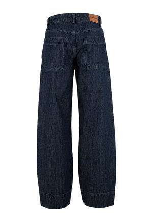 Tumši zili, plataji džinsa bikses ar divām kvadrātveida aizmugures kabatām un brūnu ādas zīmola plāksteri uz jostasvietas.