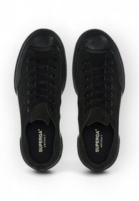 Baskets noires avec un dessus en daim et en caoutchouc, bout rond, lacets plats et détails texturés sur la cap d'orteil. Logo "SUPERGA ARTIFACT" à l'intérieur.