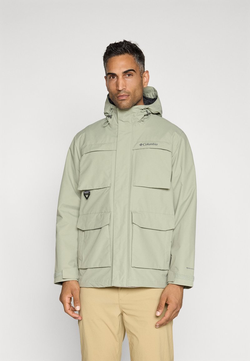 Jasnozielona wodoodporna kurtka z kapturem, wieloma przednimi kieszeniami, regulowanymi sznureczkami i logo na piersi. Gładka tekstura.