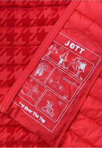 Czerwona kurtka puchowa w wzór houndstooth. Posiada białe graficzne ilustracje na wewnętrznej kieszeni, oznaczone "JOTT" i "Just Over The Top".