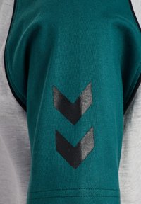 Teal fabric with a ribbed texture features black diagonal chevrons on the left side. Grey fabric is seen on the right side, smooth texture.