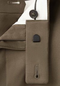 Kołnierz z tkaniny khaki z białą podszewką, wyposażony w czarny guzik, poziome przeszycia oraz przeszywaną pętelkę po boku.