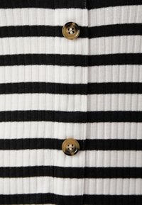 Tessuto a maglia a righe con strisce alternate in bianco e nero; presenta un bottone rotondo marrone con un motivo sottile.