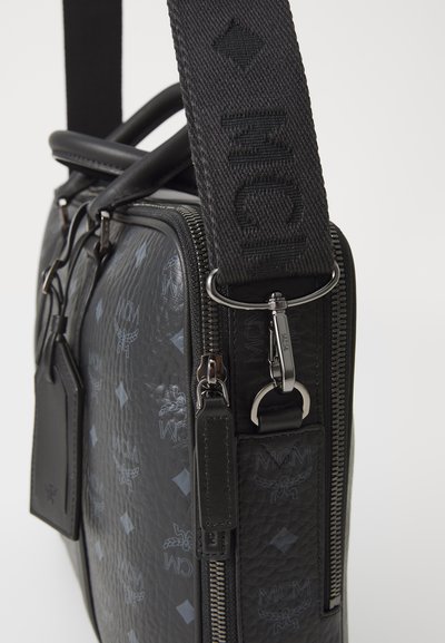 Black leather shoulder bag featuring embossed logo patterns, a dual zipper, and a woven fabric strap with logo detailing.