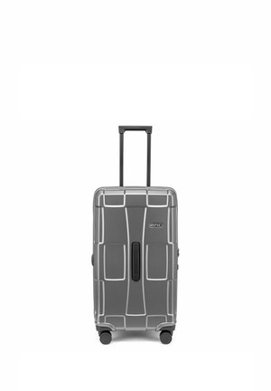 Valise rigide grise avec poignée télescopique déployée et quatre roues, debout sur fond blanc.