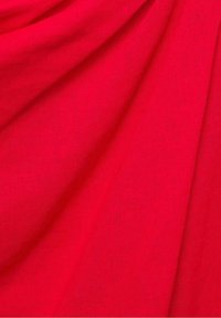 Leuchtend roter Stoff mit glatter Textur, drapiert, um subtile Falten und unterschiedliche Lichtreflexionen auf der Oberfläche zu zeigen.