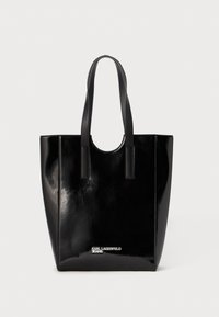 Saco tote em couro patente preto com duas alças robustas, formato retangular e uma marca discreta na parte inferior, exibindo uma textura brilhante.