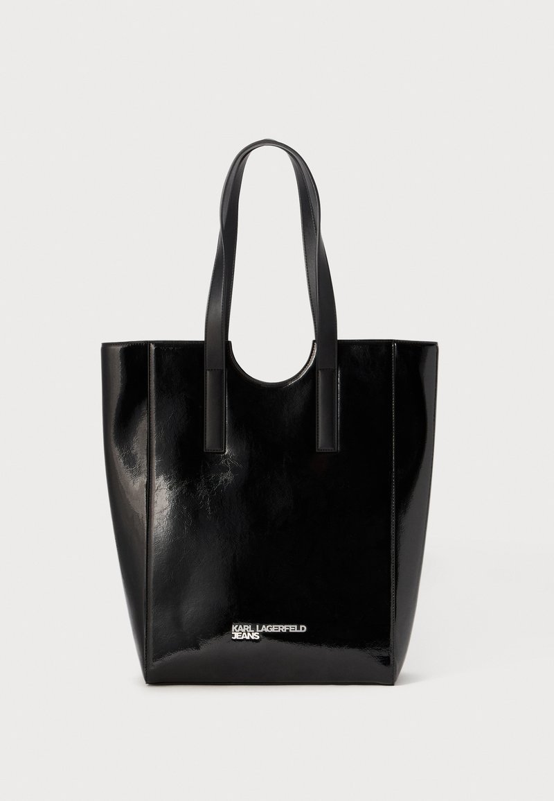 Saco tote em couro patente preto com duas alças robustas, formato retangular e uma marca discreta na parte inferior, exibindo uma textura brilhante.