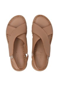 Helle Leder-Sandalen mit Überkreuzriemen und durchbrochenen Details. Komfortables Design mit flacher Sohle und sichtbaren Nähten.