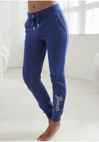 Marineblauwe joggingbroek van zacht materiaal, met een elastische tailleband met trekkoord, zijzakken en het "Bench" logo in wit op het been.