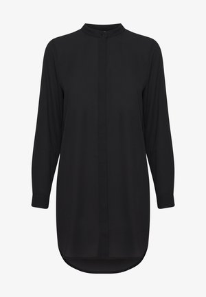 Must mustriga musta blouse, millel on mandariini kaelus, nööpkinni, sirge lõige ja veidi kaardus alläär. Kangas näeb välja sile ja kerge.