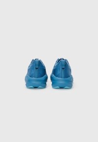Des chaussures de sport bleues avec une tige en tissu texturé, un col rembourré et une semelle en caoutchouc dotée d'un design de bande de roulement aqua contrasté.