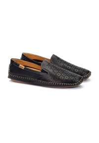 Zapatos negros sin cordones con un patrón de flores cortado a láser, parte superior de cuero, forro marrón y costuras en contraste a lo largo de la suela. Suela plana de goma.