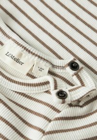 Paski body niemowlęce w kolorze kremowym i brązowym. Wykonane z teksturowanej prążkowanej tkaniny, z okrągłym dekoltem, kontrastowymi guzikami oraz metką wskazującą rozmiar.