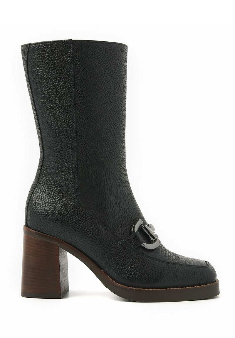 Bottine en cuir noir avec une finition texturée, un bout carré et un talon bloc en bois contrastant. Elle est dotée d'une bride décorative avec une boucle accentuée.