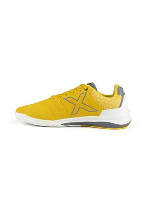 Chaussure de sport jaune et grise à lacets, grand logo "X" sur le côté, et semelle blanche avec des accents gris et jaunes.