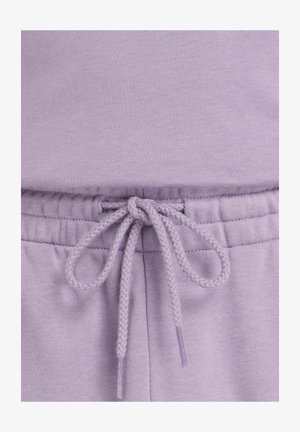 Close-up of lavender sweatpants waistband with a tied braided drawstring and ribbed elastic stitching.