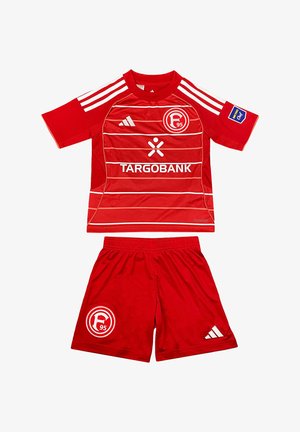 Equipación de fútbol del Fortuna Düsseldorf en rojo con rayas blancas, logotipos de patrocinadores y escudo del club en la camiseta y los pantalones cortos.