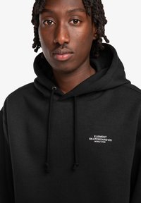 Black hoodie made of soft cotton blend, featuring a front pouch pocket and drawstrings, with white logo embroidery on the chest.