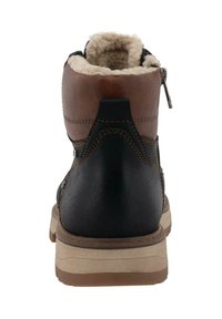 Zadní pohled na zimní botu z hnědé a černé kůže s béžovým fleecem uvnitř a béžovou gumovou podrážkou.