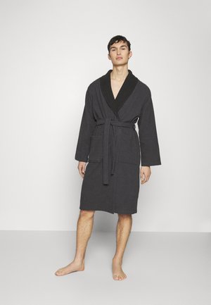 Peignoir noir en tissu doux avec un col châle noir, des manches longues, une ceinture à nouer et deux poches avant. Texture douce, coupe longueur genoux.