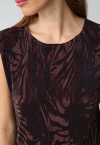 Zwart en burgundy ribstof met een gestructureerd zebra-patroon, voorzien van een ronde halslijn en korte mouwen.