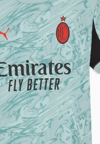 Maglia da calcio azzurro chiaro con maniche nere, caratterizzata da un motivo astratto testurizzato, logo rosso e scritta nera "Emirates FLY BETTER."