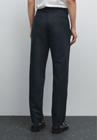Pantaloni blu scuro realizzati in un tessuto liscio, con taglio dritto, tasche laterali e tasche posteriori, completati da un design semplice e pulito.