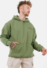 Felpa con cappuccio verde oliva, dotata di tasca frontale, polsini a costine e un piccolo logo ricamato. Realizzata in un morbido tessuto testurizzato.