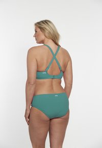 Completo bikini in teal con spalline incrociate. La parte superiore presenta una chiusura a gancio. Texture liscia con dettagli del logo su entrambi i pezzi.