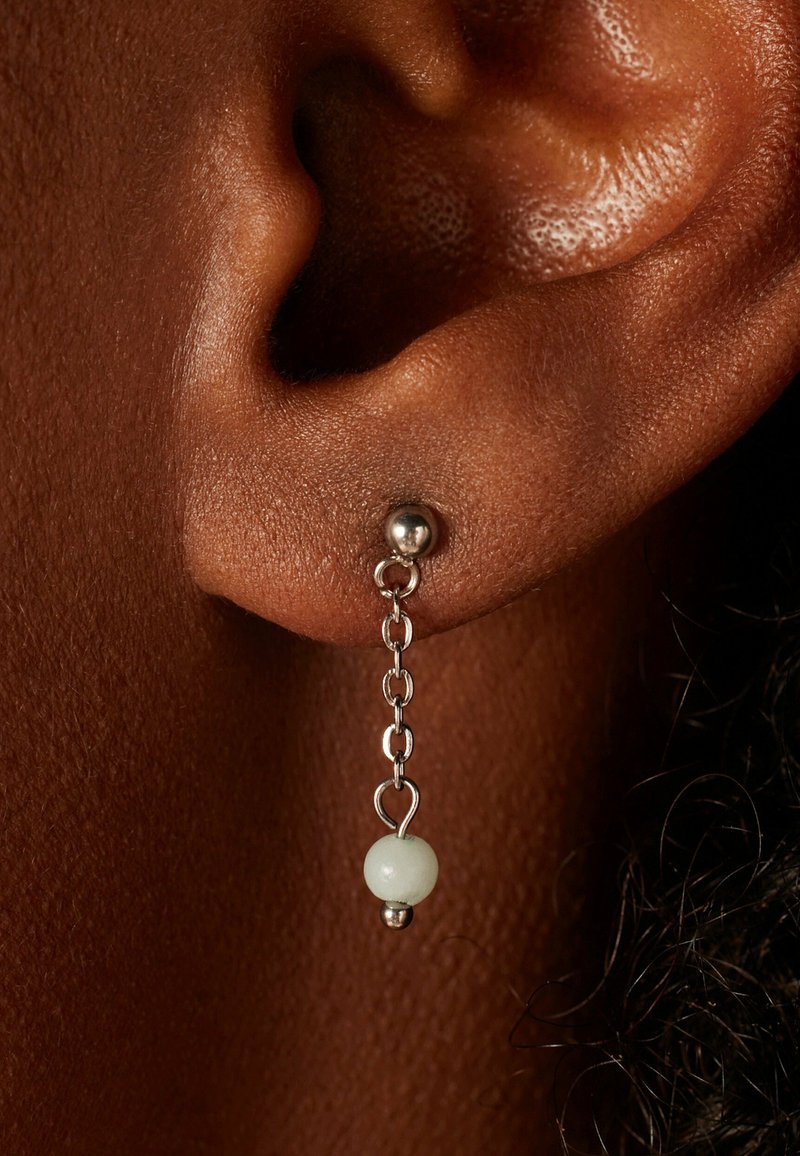 Boucles d'oreilles en argent avec une perle ronde et un détail en chaîne, mettant en avant une finition polie et une perle blanche translucide à l'extrémité.