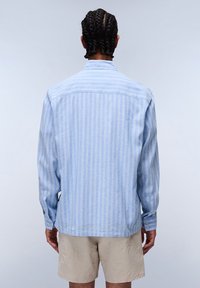 Camisa de rayas azul claro hecha de tejido entrelazado, con un cuello tipo polo, puños abotonados y un ajuste ligeramente holgado.