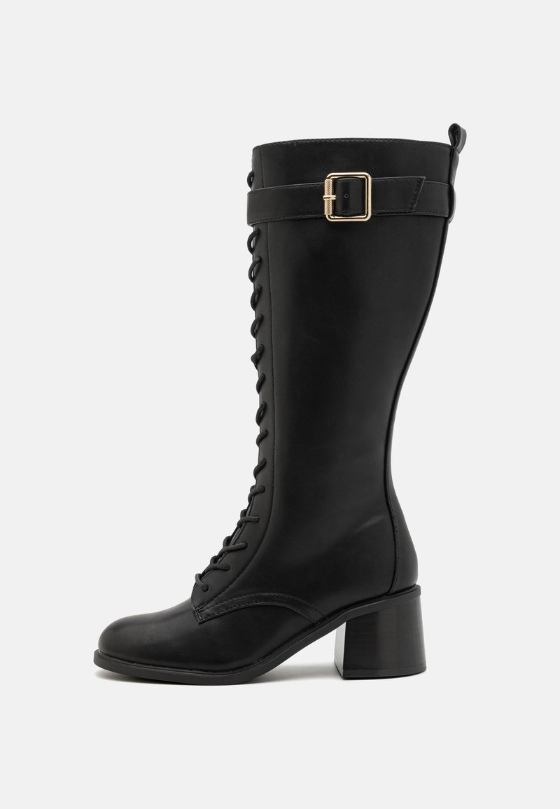 Juoda odinė iki kelių boot su kvadratiniu pirštu, raišteliu priekyje ir šone esančia sagtimi. Kvadratinis kulnas suteikia stabilumo ir aukščio.