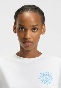 Witte sweatshirt met een ronde hals, voorzien van een blauwe geborduurde zonontwerp en 'Hugo' tekst op de linkerborst, gemaakt van zachte katoenstof.