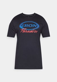 Czarny t-shirt z krótkim rękawem z niebieskim owalnym logo i czerwonym napisem "Paradise" na przodzie.