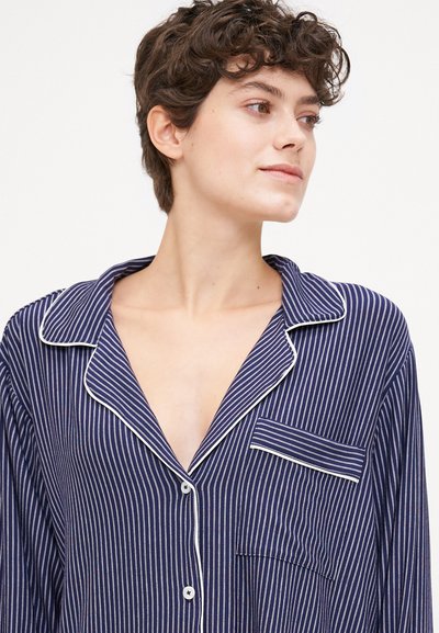 Navy striped pajamas with white piping, featuring a notch collar, button front, and pocket. Lightweight fabric with vertical stripes.