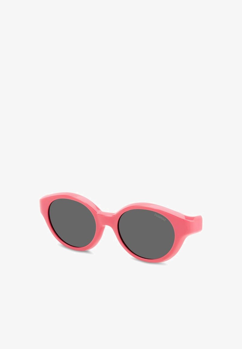 Des lunettes de soleil en plastique rose avec des verres ovales surdimensionnés et une teinte gris foncé. La texture lisse et les branches larges augmentent le confort et la couverture.