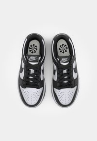 Black and white Nike sneakers feature smooth leather, perforated toe, round laces, and a gray insole with a flower design.
